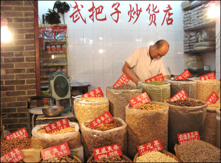 A seller arranges nuts in a market on East Street, of Xi'an.