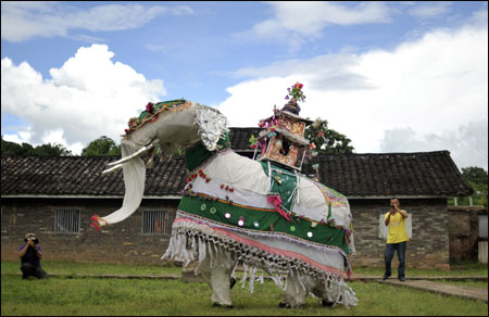 Tourists take pictures at the white elephant dance folk performance at a tourism resort in Jinggu county, Yunnan province.