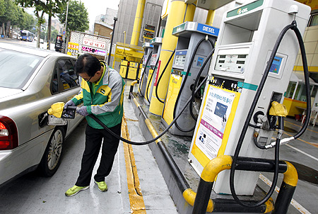 An employee fills the tank of a car at a petrol station in Seoul.