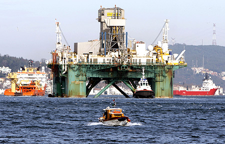 A fishing boat passes in the foreground as the Leiv Eiriksson, an oil drilling platform, makes its way through the Bosphorus in Istanbul.