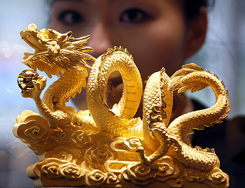 A sales representative poses behind a nine-tael 24K gold in the shape of a dragon forming the numerals 2012.