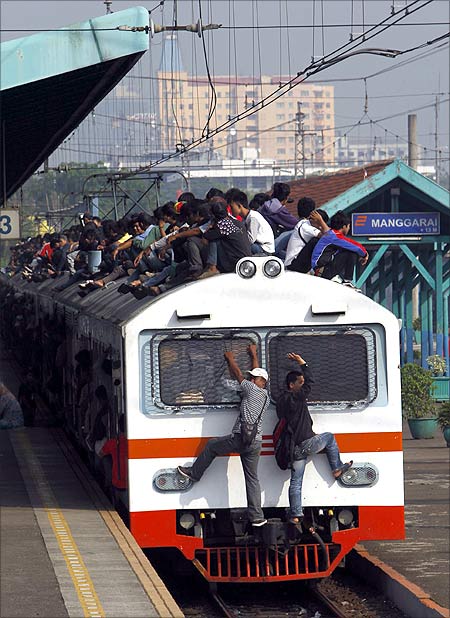 Passengers sit on the rooftop of a commuter train as it arrives at the Manggarai train station in Jakarta.