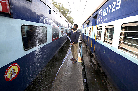 Railway employees wash a passenger train at a railway station in Jammu.