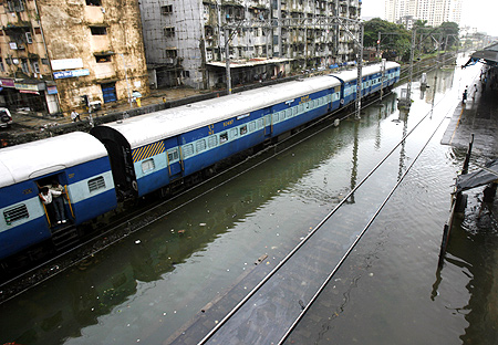 A train runs on flooded tracks on a rainy day in Mumbai.