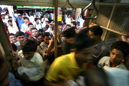 Commuters rush into a suburban train at a railway station in Mumbai.