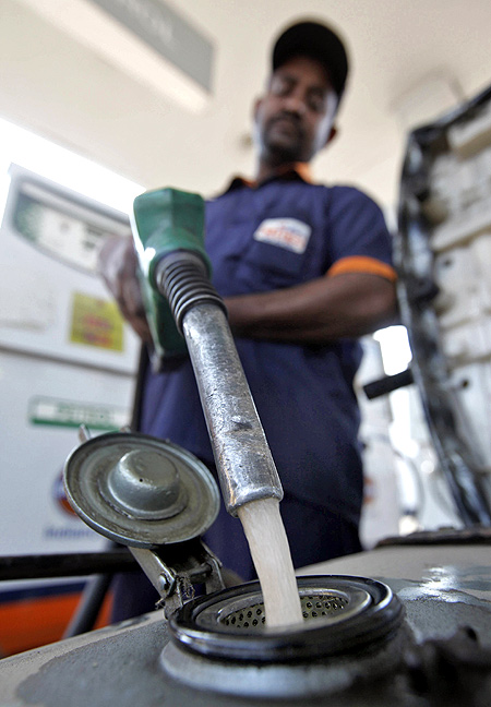 A worker fills petrol in a scooter at a fuel station in Kolkata