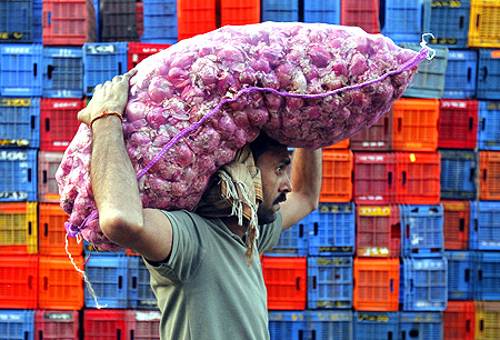 A labourer carries onions at a wholesale market in Mumbai.