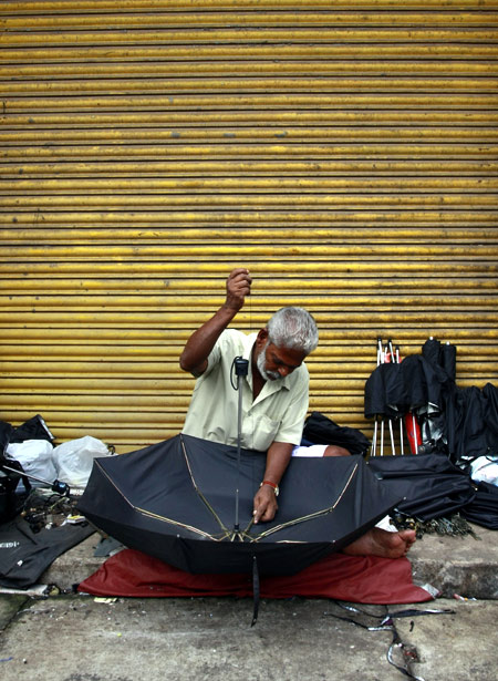 A man repairs an umbrella at his roadside stall in Kochi.