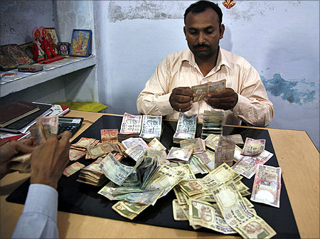 Employees at a wholesale shop count money in Allahabad.