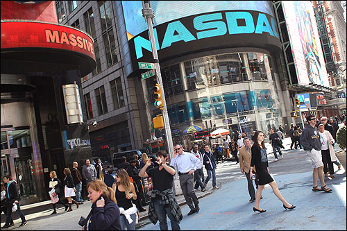 Pedestrians walk past the Nasdaq stock market at Times Square.