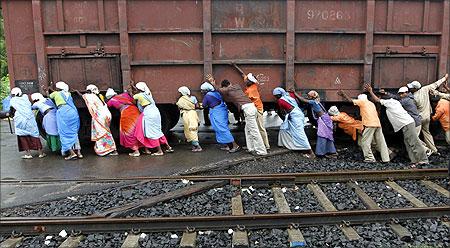 Railway workers push a wagon loaded with coal back to its track after it derailed at Sabarmati power house in Ahmedabad.