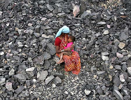 A worker breastfeeds her child during lunch break at a coal yard in Jammu.