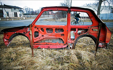 A cyclist is seen through a part of a Fiat 126 car, nicknamed