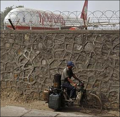 A cyclist rides past a perimeter wall at Mumbai's domestic airport, behind which a decommissioned Kingfisher Airlines aircraft is parked.