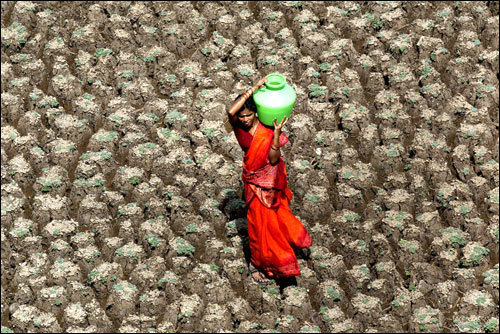 A woman carries a pot of water home, taking a short cut across the dry bed of the Usmansagar lake, in Hyderabad, capital of the south Indian Andhra Pradesh state, June 6, 2003.