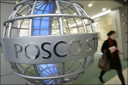 A woman walks past a sculpture of POSCO's logo at its headquarters in Seoul.