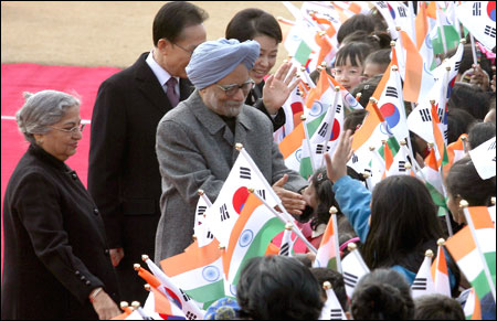 Prime Minister Manmohan Singh(C) and his wife Gursharan Kaur (L) greet South Korean children during a welcoming ceremony held at the Presidential house.