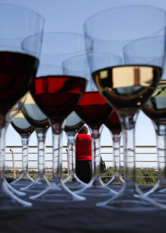 A woman attends the Vivanda Taste the Med food festival as glasses of red and white wine are placed on a display table at Ta Qali, outside Valletta, Malta.