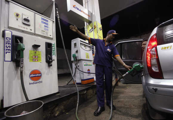 A worker fills a car with petrol.