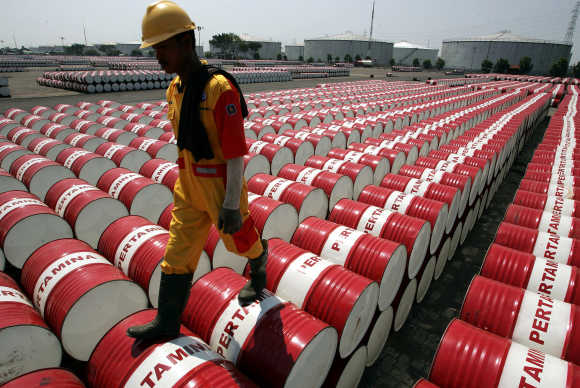 An employee of Indonesian oil company Pertamina walks on the top of drums at the oil storage depot in Jakarta.
