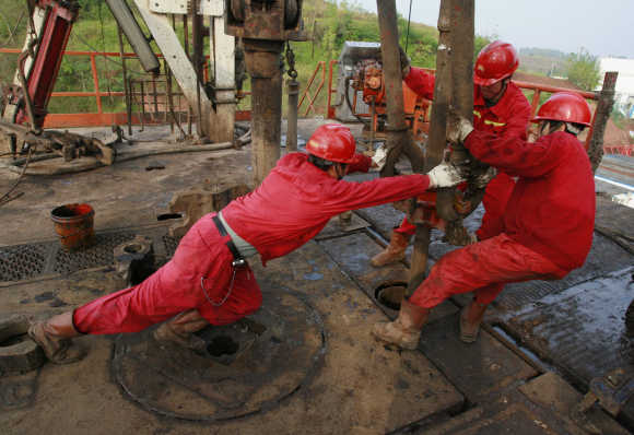 Labourers work at a well head in a PetroChina oil field in Tongnan, southwest China's Sichuan province.