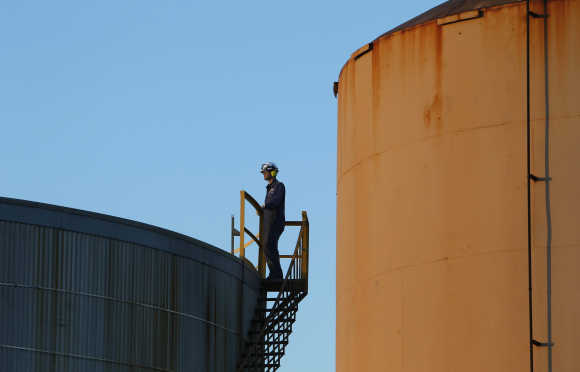 A worker is seen on top of a fuel storage tank at an oil refinery in Melbourne.