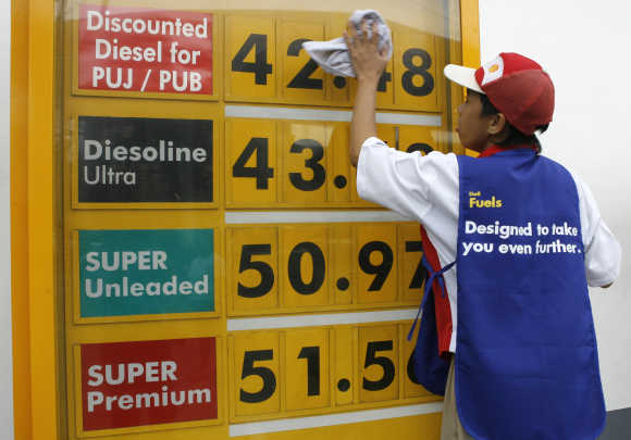 A worker wipes the price display board at a petrol station in Manila.