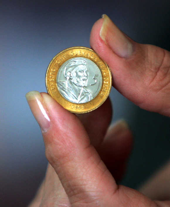 Cuban woman holding new convertible five peso coin bearing the face of Che Guevara.
