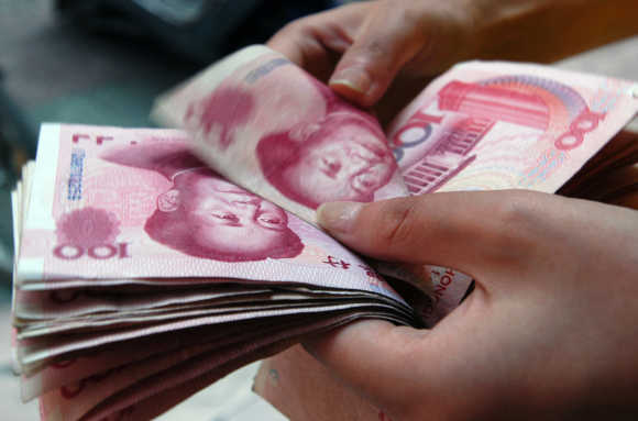 Shop assistant checks hundred yuan bank notes at shop in Xiangfan, China.