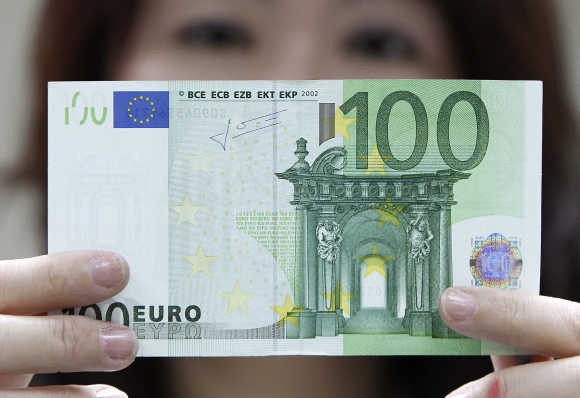 An employee checks a euro note at the Bank of Taiwan in Taipei.