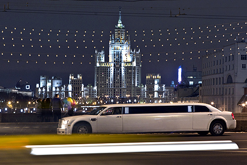 Cars drive past sightseers on a bridge over the Moskva river near a Stalin era skyscraper in central Moscow.