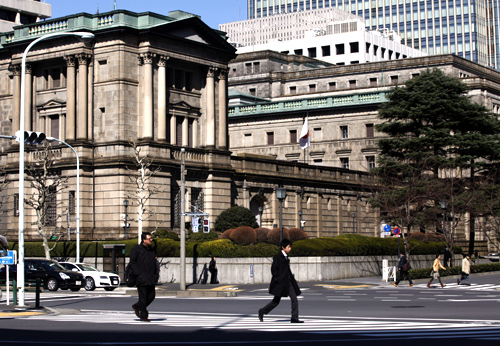 Pedestrians cross a street in front of the Bank of Japan (BOJ) headquarters building in Tokyo.