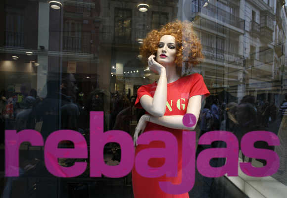 People are reflected on a shop window in Seville, Spain.