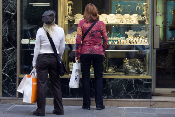 Women carry shopping bags as they look at a window display of a jewellery shop in central Paris.