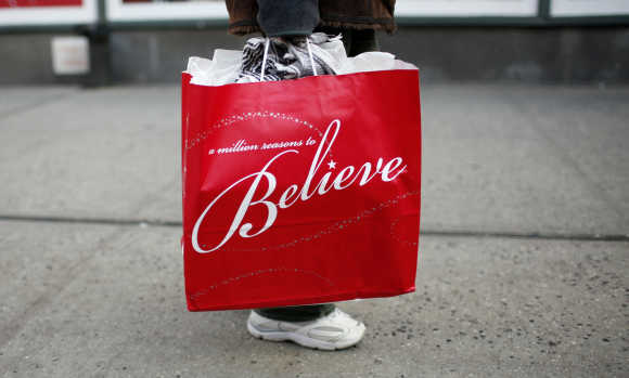 A woman carries a shopping bag from Macy's department store as she walks along 34th street in New York City.