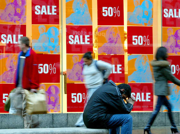 Shoppers pass sales signs in shop windows in Oxford Street, London.