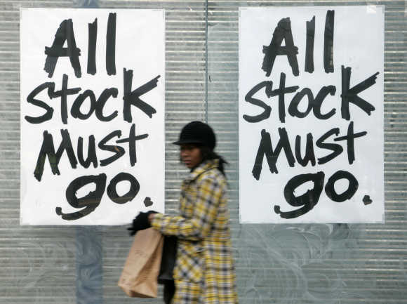 A woman passes a sign saying 'All Stock Must Go' in Croydon, London.