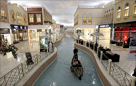 A family takes a sampan ride on a canal inside Villagio Mall, a popular shopping area in Doha.
