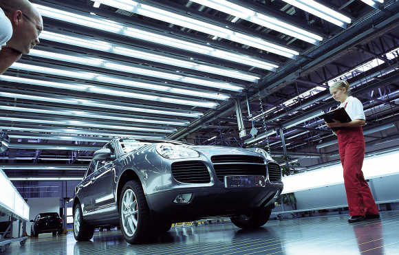 Workers perform a quality check on a Cayenne car at the Porsche factory in Leipzig, Germany.