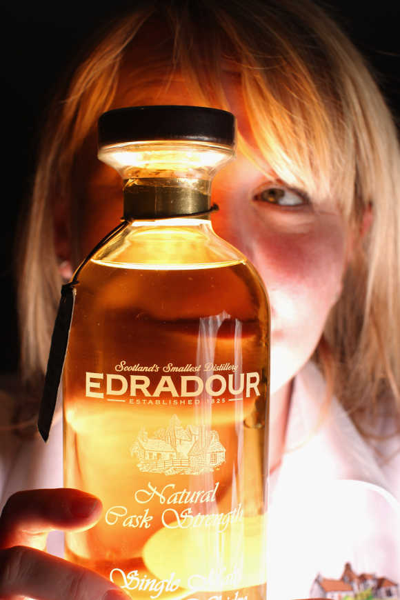 Julie Cameron, tour guide, holds a bottle of whisky at Edradour distillery.