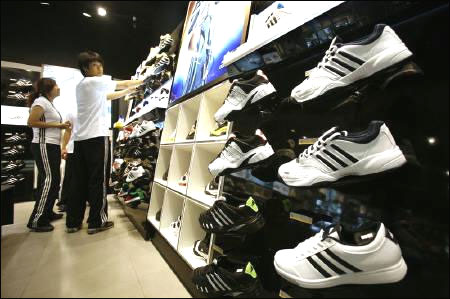 Staff arrange shoes at Adidas Brand Center store in Beijing.