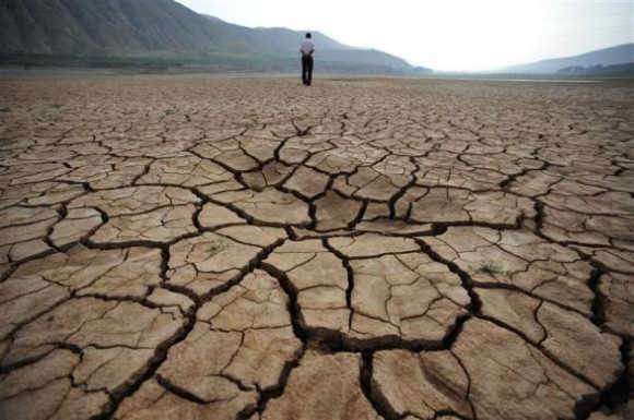 A local resident walks on a dried-up riverbed at Huangyangchuan reservoir in Lanzhou, Gansu province, China.