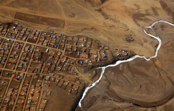 A frozen river is seen next to a group of houses located on the outskirts of the Mongolian capital city of Ulan Bator.