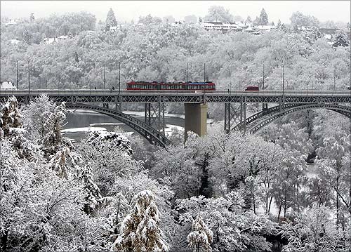 A tramway crosses the 'Kirchenfeld' bridge during snowfall in Bern.