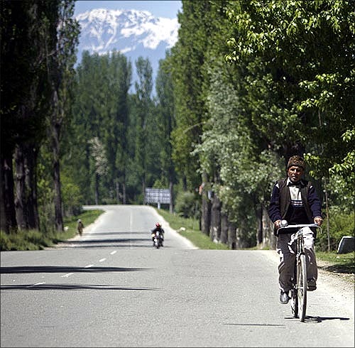 A man rides a bicycle on a deserted highway, north of Srinagar.