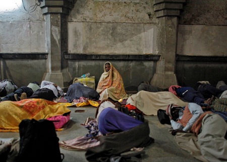 Commuters rest outside the ticket counter at a railway station in the old quarters of Delhi.