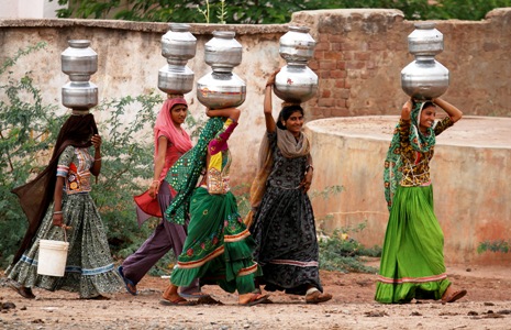 Women carry metal pitchers filled with drinking water at Charnaka village, Gujarat.
