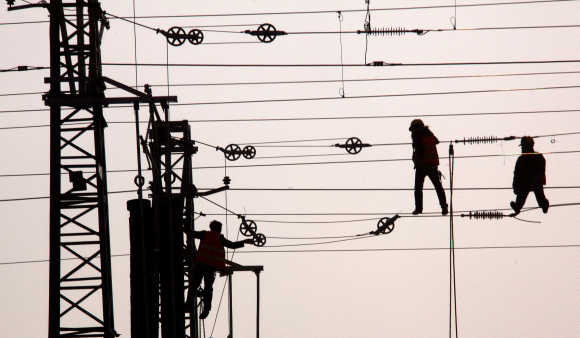 Workmen hang from the power lines for a new railway line under construction on the outskirts of Beijing.