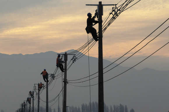Workers repair electricity pylons and wires in a rural area near Santiago.