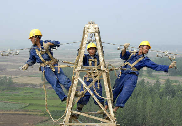 Labourers repair electricity cables on a power tower in Chuzhou, China.